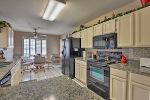 A kitchen with white cabinets, a black refrigerator, a stove, and a microwave. There is a dining area with a table and chairs. - Golf, Hike & Suntan: Mesa Family Home w/ Yard (Mesa)