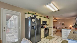 A kitchen with white cabinets, a stainless steel refrigerator, a microwave, and a stove. There is a dining area with a chair and a table. - Golf, Hike & Suntan: Mesa Family Home w/ Yard (Mesa)