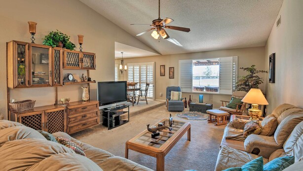 A living room with a ceiling fan, a TV, a coffee table, sofas, and a dining area with chairs and a table. - Golf, Hike & Suntan: Mesa Family Home w/ Yard (Mesa)