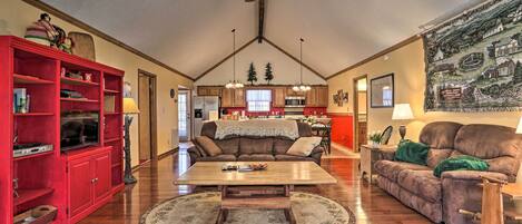A spacious living room with a wooden coffee table, red shelving unit, and a ceiling fan.