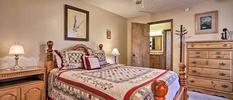 Ein Schlafzimmer mit einem hölzernen Bett, einem Nachttisch, einer Kommode und einem Deckenventilator.