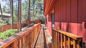 Um deck de madeira leva a um edifício vermelho com porta e janela.