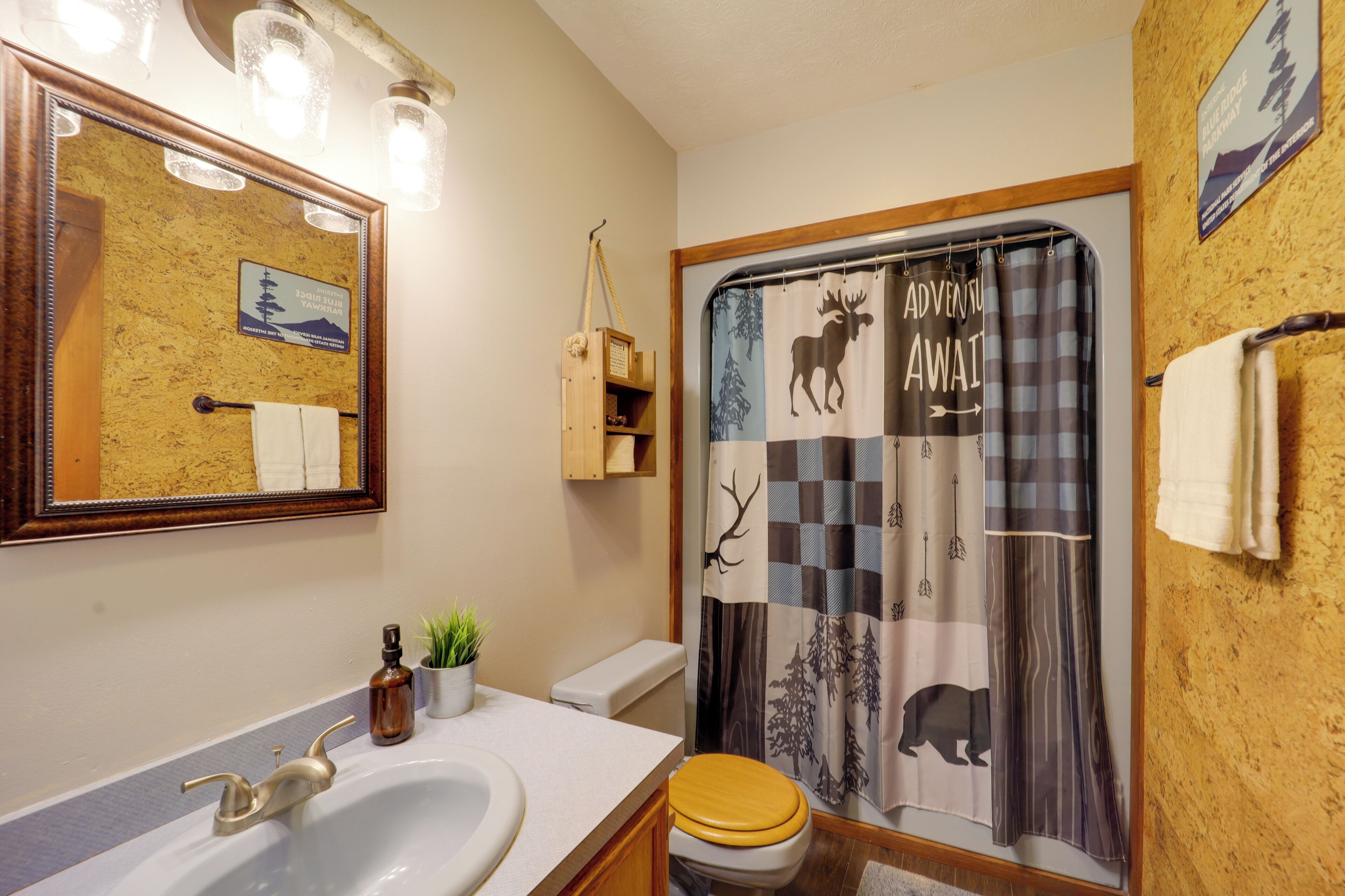 Un baño con lavamanos, espejo y cortina de ducha con estampados de animales.