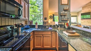 A modern kitchen with granite countertops, stainless steel appliances, and wooden cabinets. - Cozy Wintergreen Resort Condo: Walk to Ski Lifts! (Roseland)