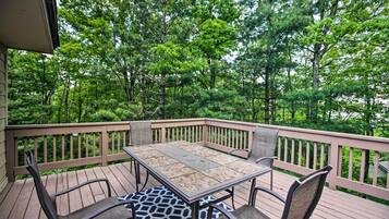 A wooden deck with a table and chairs, surrounded by trees.
