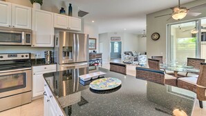 A modern kitchen with stainless steel appliances, a central island, and a dining area with wicker chairs.