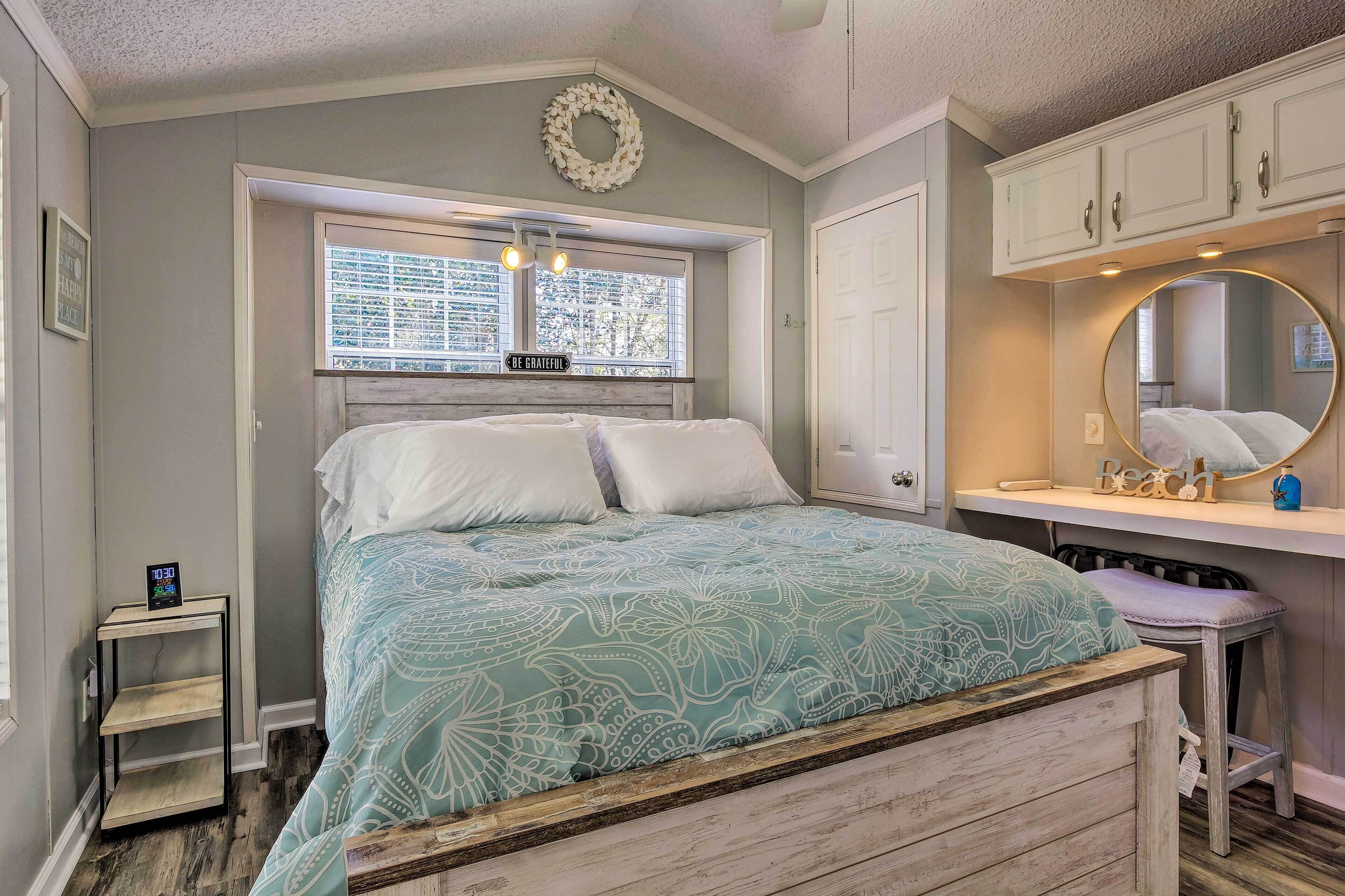 A bedroom with a bed, a nightstand, a window, a mirror, and a wardrobe.