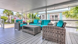 A covered outdoor seating area with wicker furniture and teal cushions, overlooking a residential area with palm trees and a house with a blue roof. - 2.5 Blocks to Beach! Miramar Tropical Cabana' (Miramar Beach)