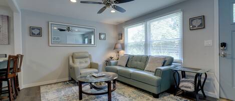 A living room with a ceiling fan, a sofa, a coffee table, and a dining area with chairs.