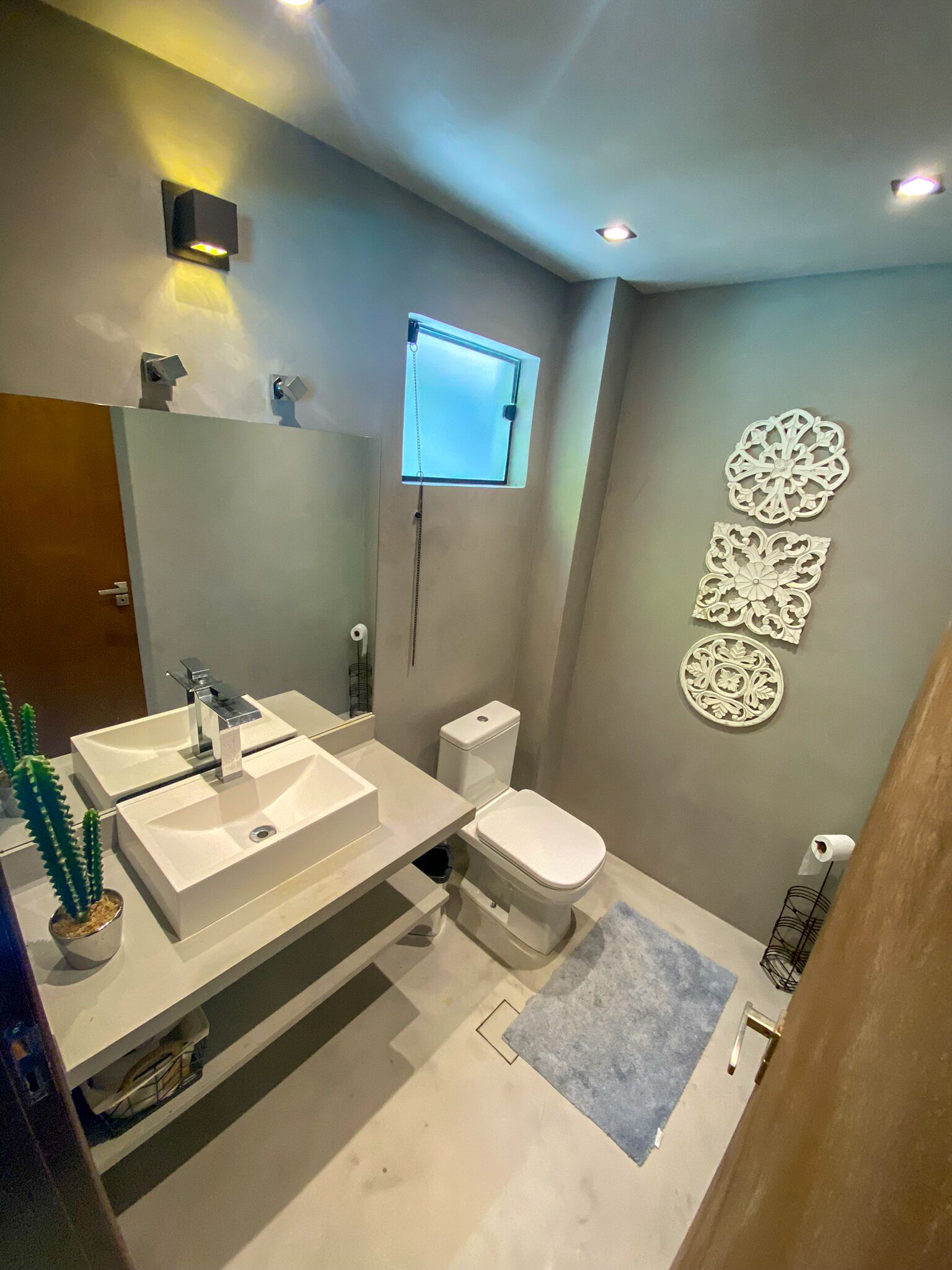 Ein modernes Badezimmer mit einem großzügigen Waschtisch, einer Toilette und einer Wandleuchte.