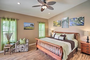 A bedroom with a wooden bed, a chair, a table, and a ceiling fan. - Elegant Lake Havasu Getaway w/ Pool - 3 Mi to Lake (Lake Havasu City)
