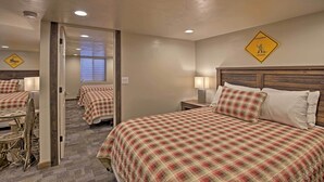 A hotel room with a checkered bedspread, a wooden headboard, a nightstand with a lamp, and a mirror.