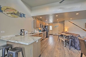 A modern kitchen with a marble countertop, wooden cabinets, and a built-in island with bar stools.