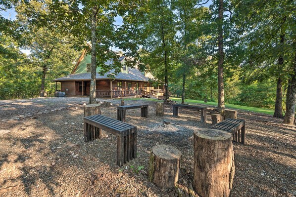 Un chalet rustique doté d’un porche, entouré d’un espace recouvert de gravier, avec des bancs en bois et une table de pique-nique.