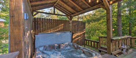 Un jacuzzi de madera bajo una estructura cubierta, con una terraza y barandillas de madera.