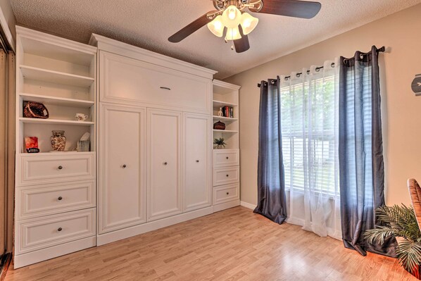 A spacious room with a large white wardrobe, a ceiling fan, and a window with curtains. - Centrally Located Deltona Home With Pool & Yard (Deltona)