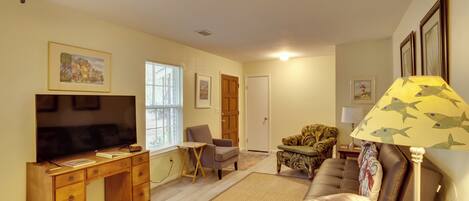 A living room with a wooden desk, television, and comfortable seating.