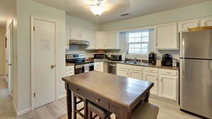 A kitchen with white cabinets, stainless steel appliances, a wooden island, and a window providing natural light. - Downtown Home w/ Yard & BBQ - 6 Mi to Downtown! (Beaufort)