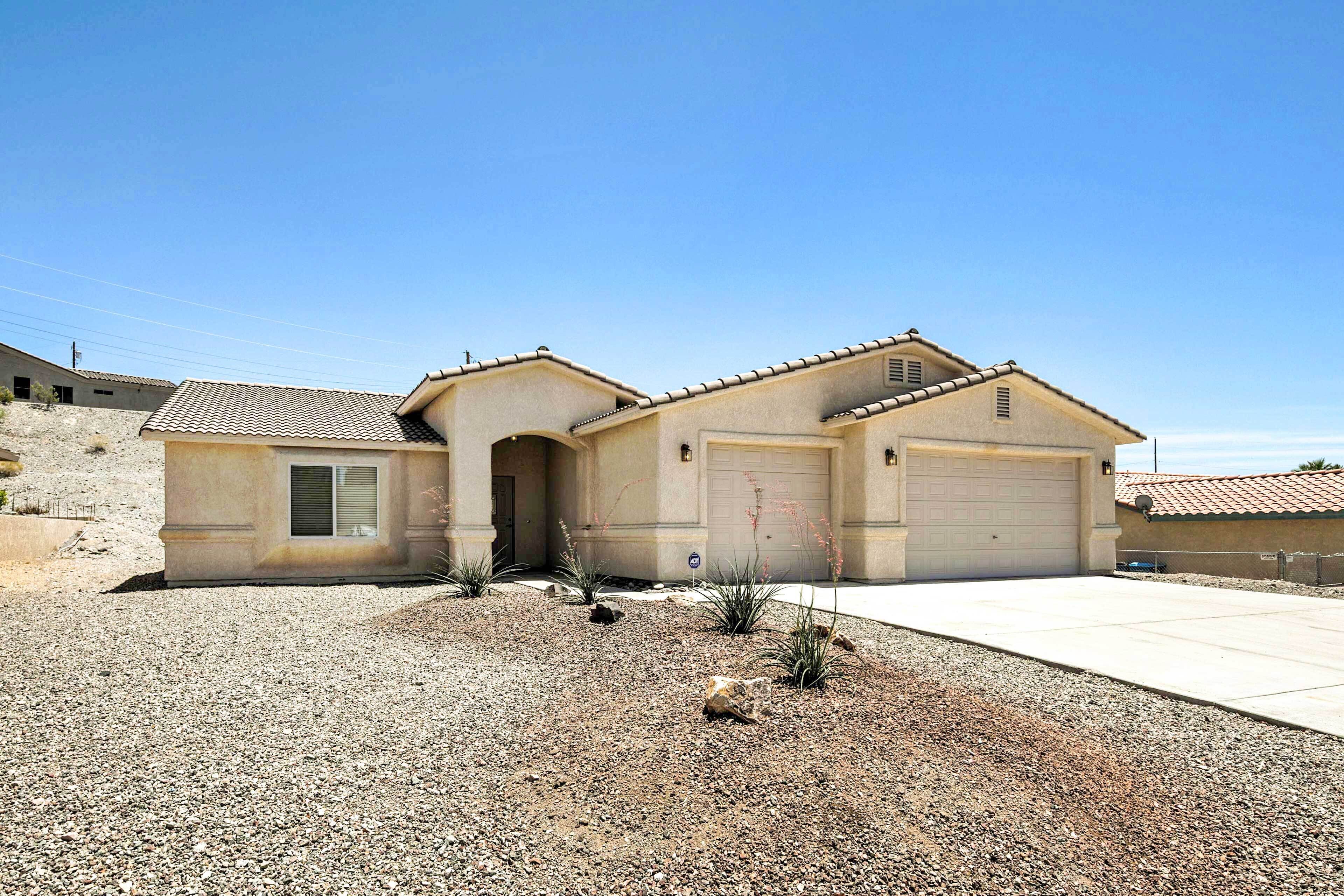 A single-story house with a garage, a small front porch, and a gravel driveway.