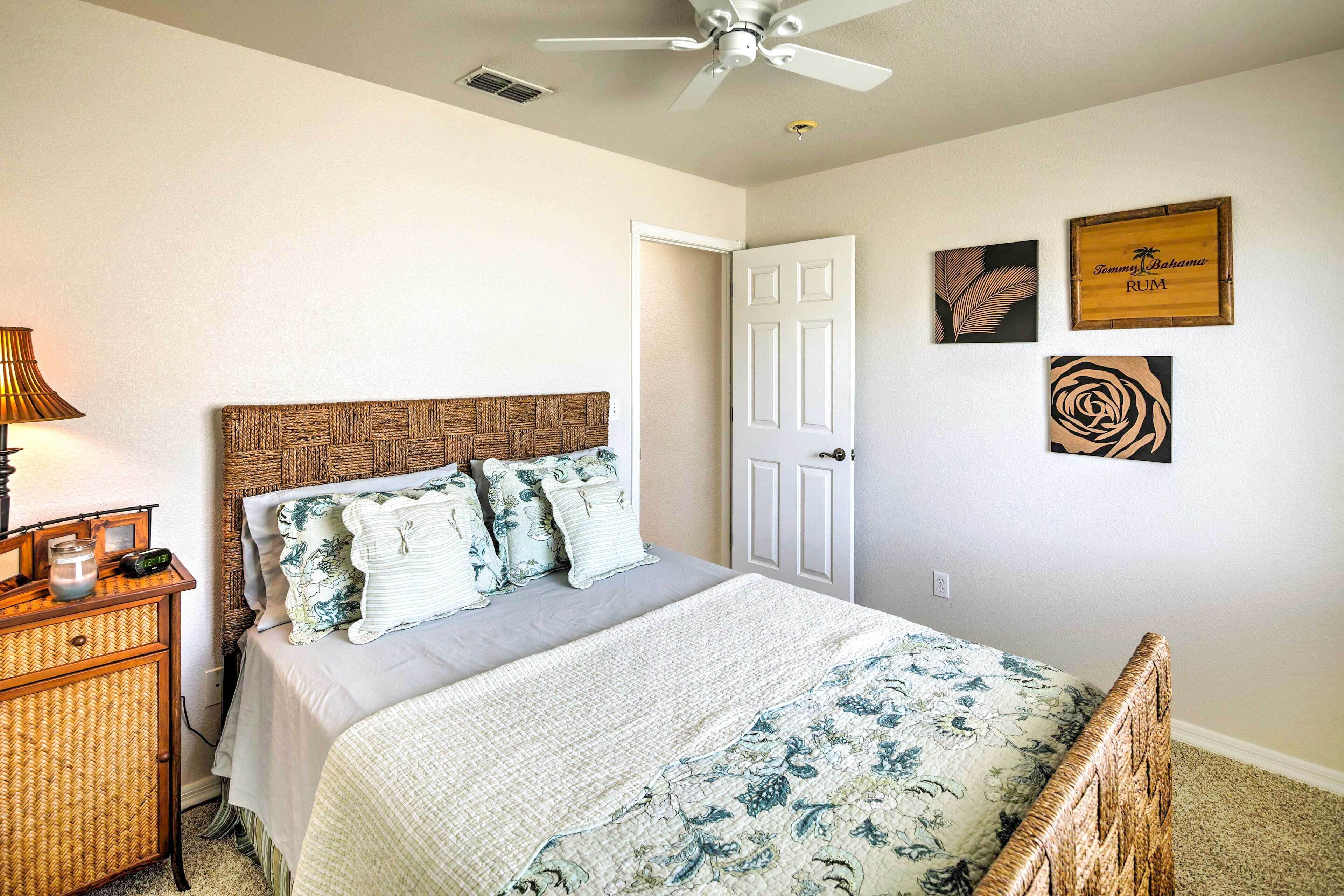 A bedroom with a bed, bedside table, lamp, and wall art.