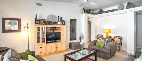 A living room with a television, wooden cabinet, and two sofas.