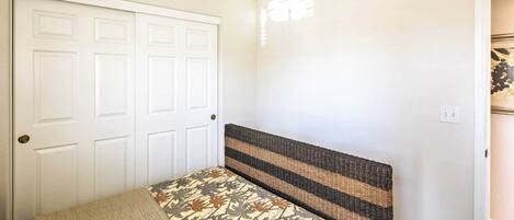 Un dormitorio con cama, ventilador de techo y puerta blanca.