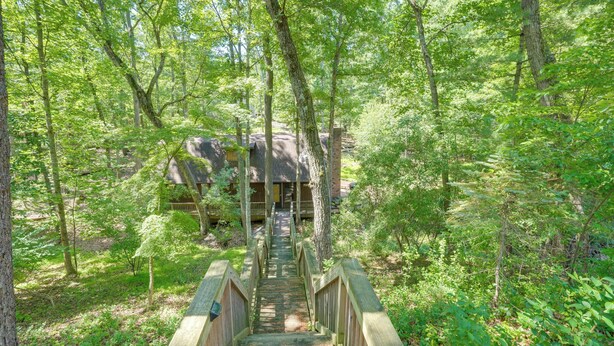 A wooden bridge leading to a cabin in a forest.