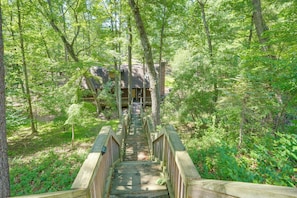 A wooden bridge leading to a cabin in a forest.
