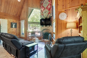 A wooden interior with leather sofas, a fireplace, a television, and a clock.