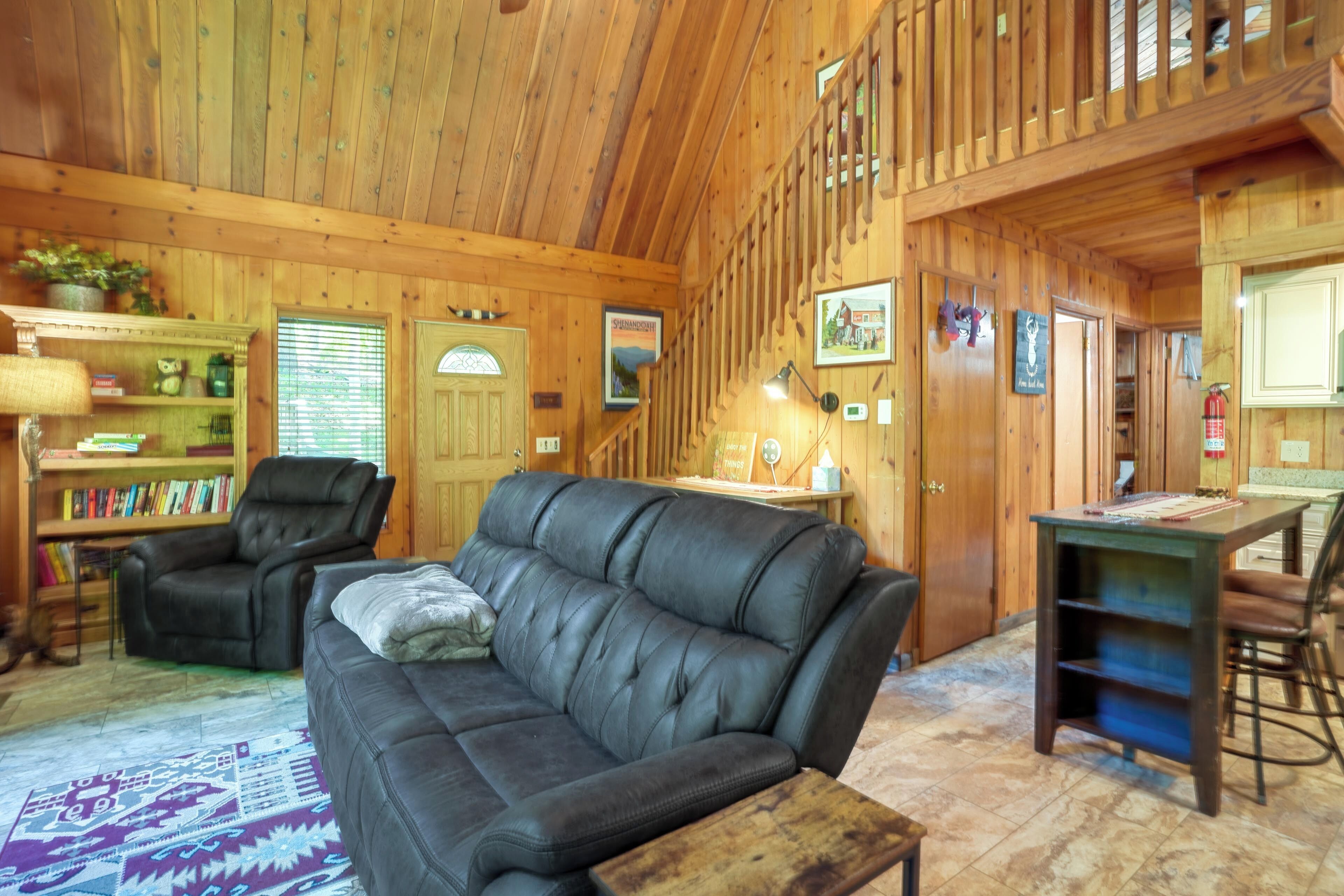 L’intérieur d’un chalet chaleureux, avec un canapé en cuir, une table à manger et une bibliothèque.