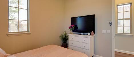 A bedroom with a bed, a dresser, a television, and a window.