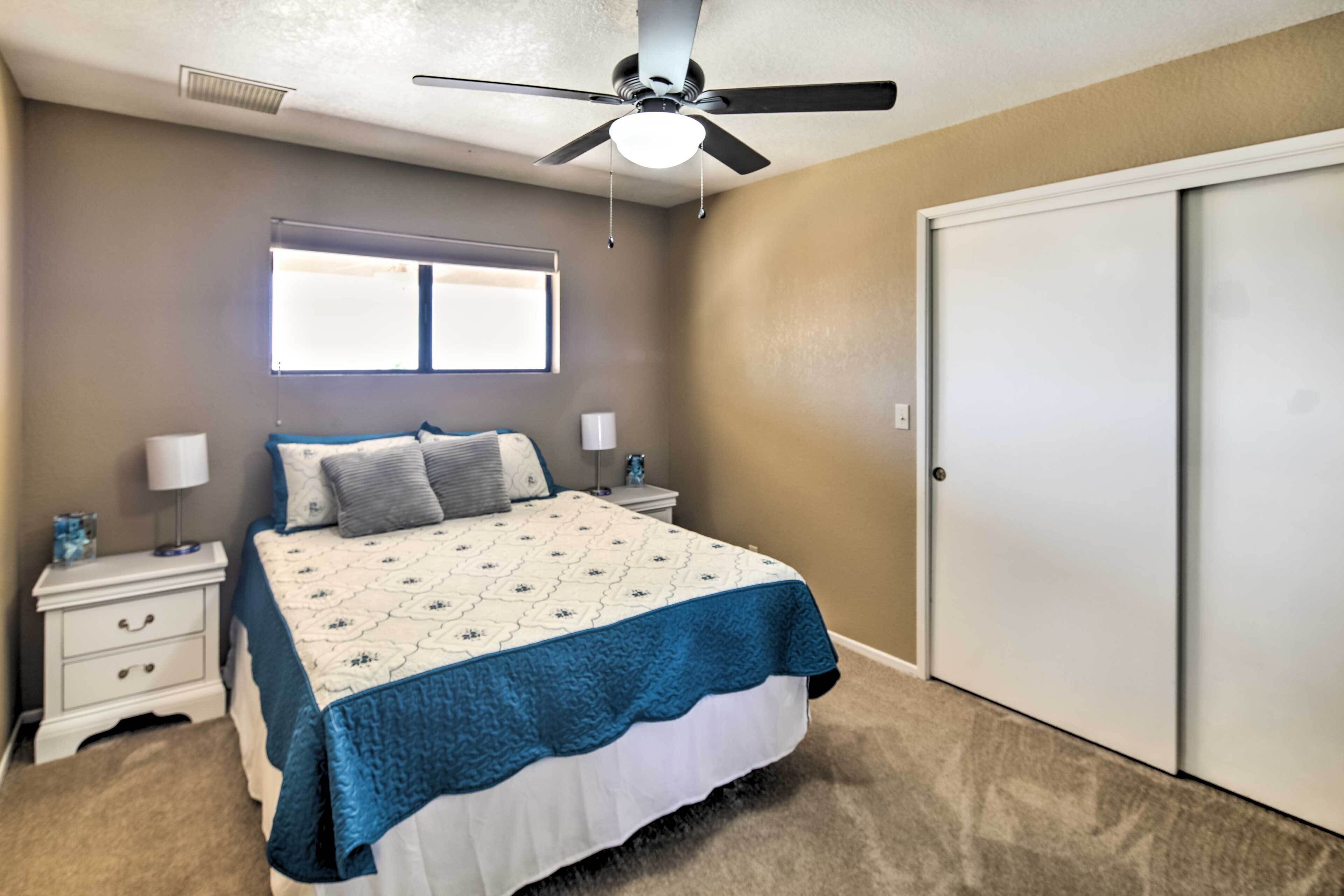 A bedroom with a bed, nightstands, a ceiling fan, a window, and a closet.
