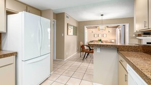 A modern kitchen with a central island, built-in appliances, and a dining area with chairs.