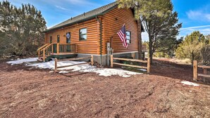 Eine Holzhütte mit Veranda, einer amerikanischen Flagge und einem Kranz an der Tür.