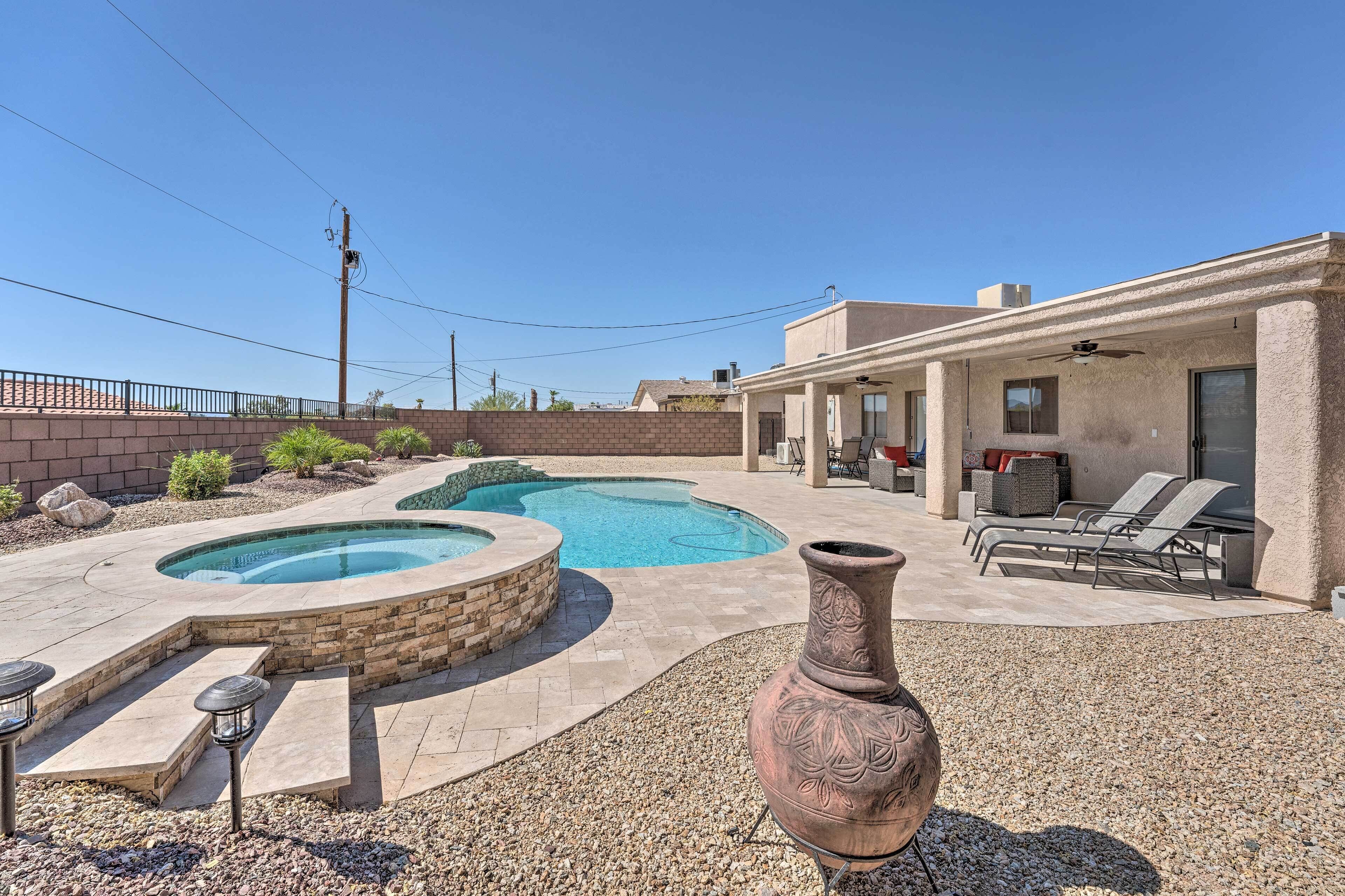A backyard with a swimming pool, a patio area with lounge chairs, and a large decorative vase.