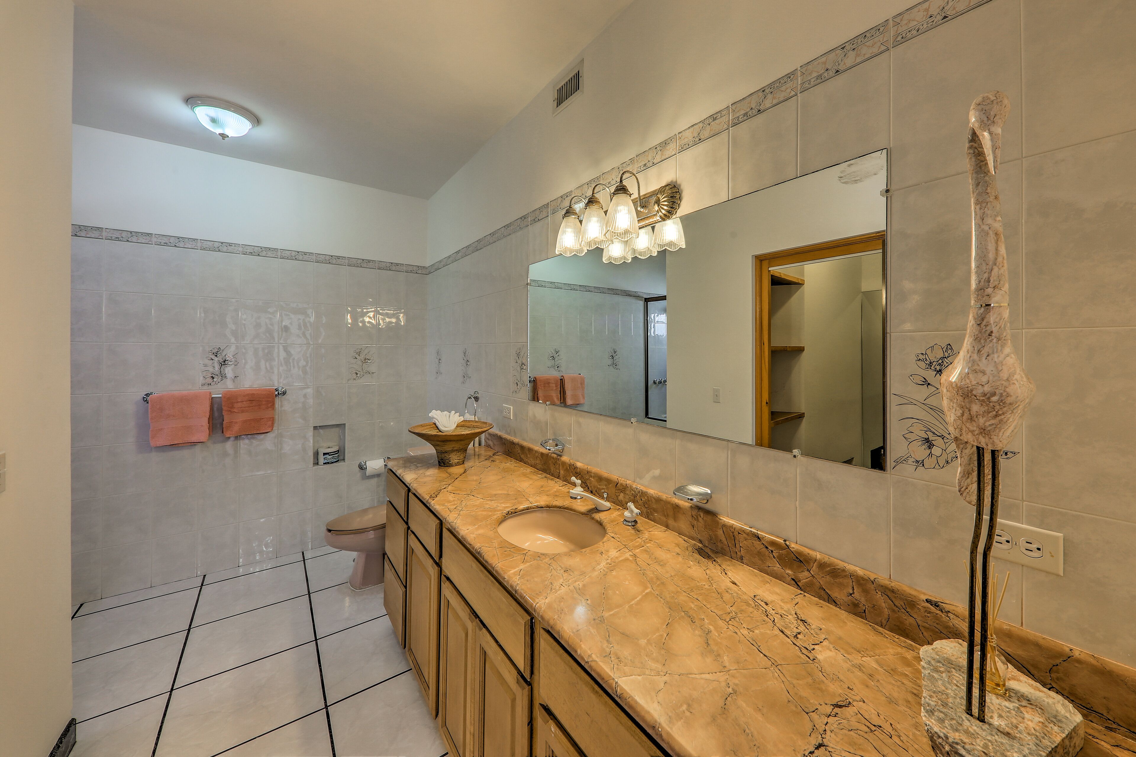 A bathroom with a marble sink, a large mirror, and a towel rack.