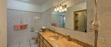 A bathroom with a marble sink, a large mirror, and a towel rack.