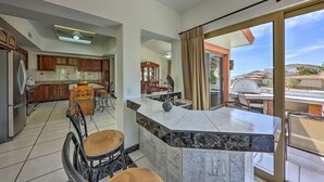 Una cocina moderna con encimeras de mármol, una isla central y un comedor con sillas.