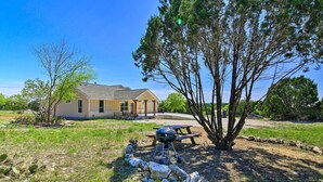 A house with a patio area, a barbecue grill, and a stone wall.