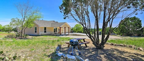 A house with a patio area, a barbecue grill, and a stone wall.