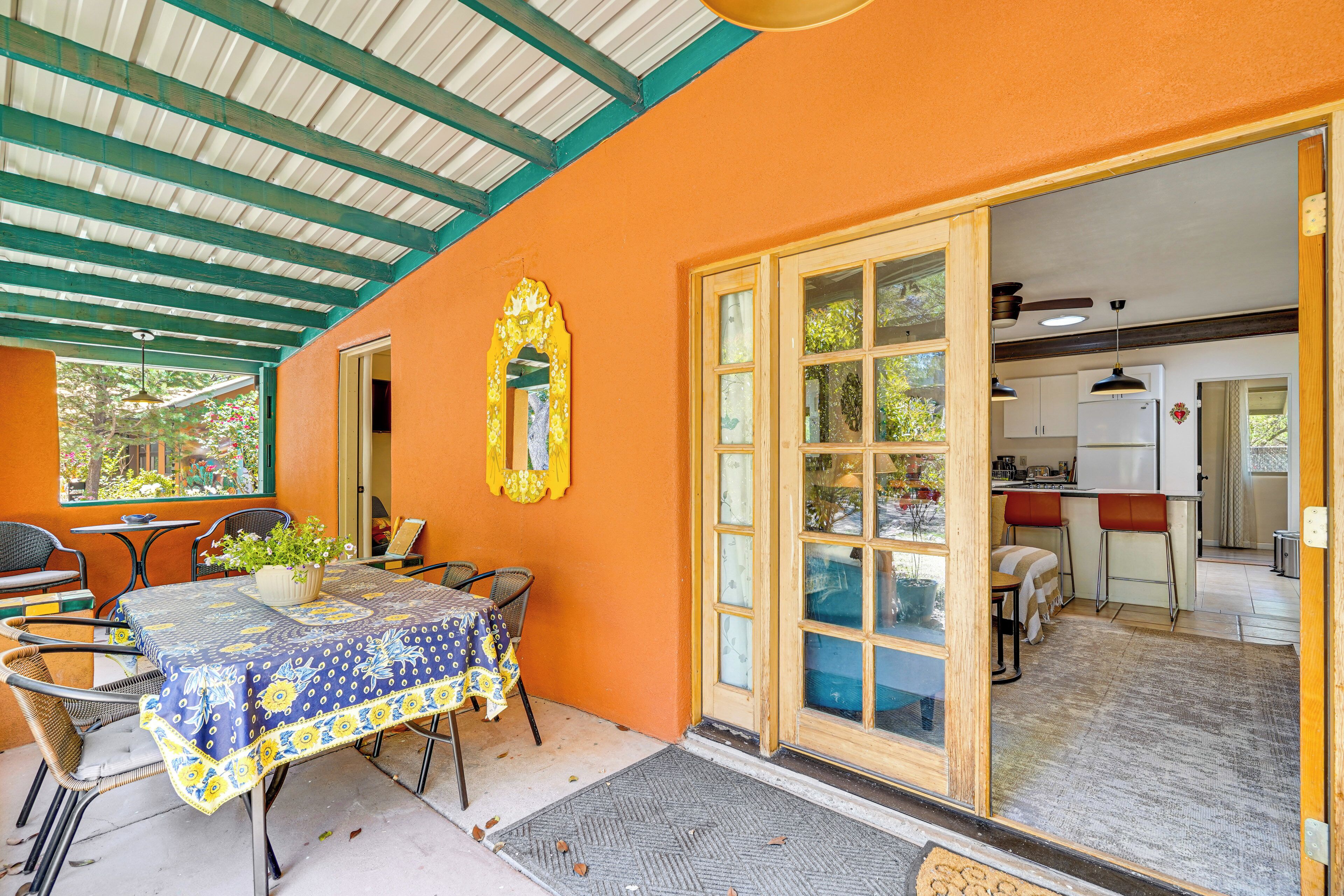 Un patio al aire libre con una mesa, sillas, una planta en maceta y una puerta que da a una cocina.