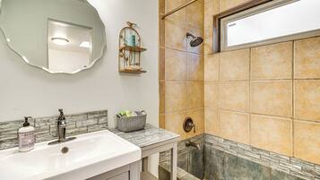 A bathroom with a sink, mirror, shower, and decorative items.