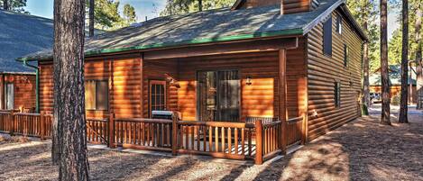 A log cabin with a porch, a chimney, and a window.