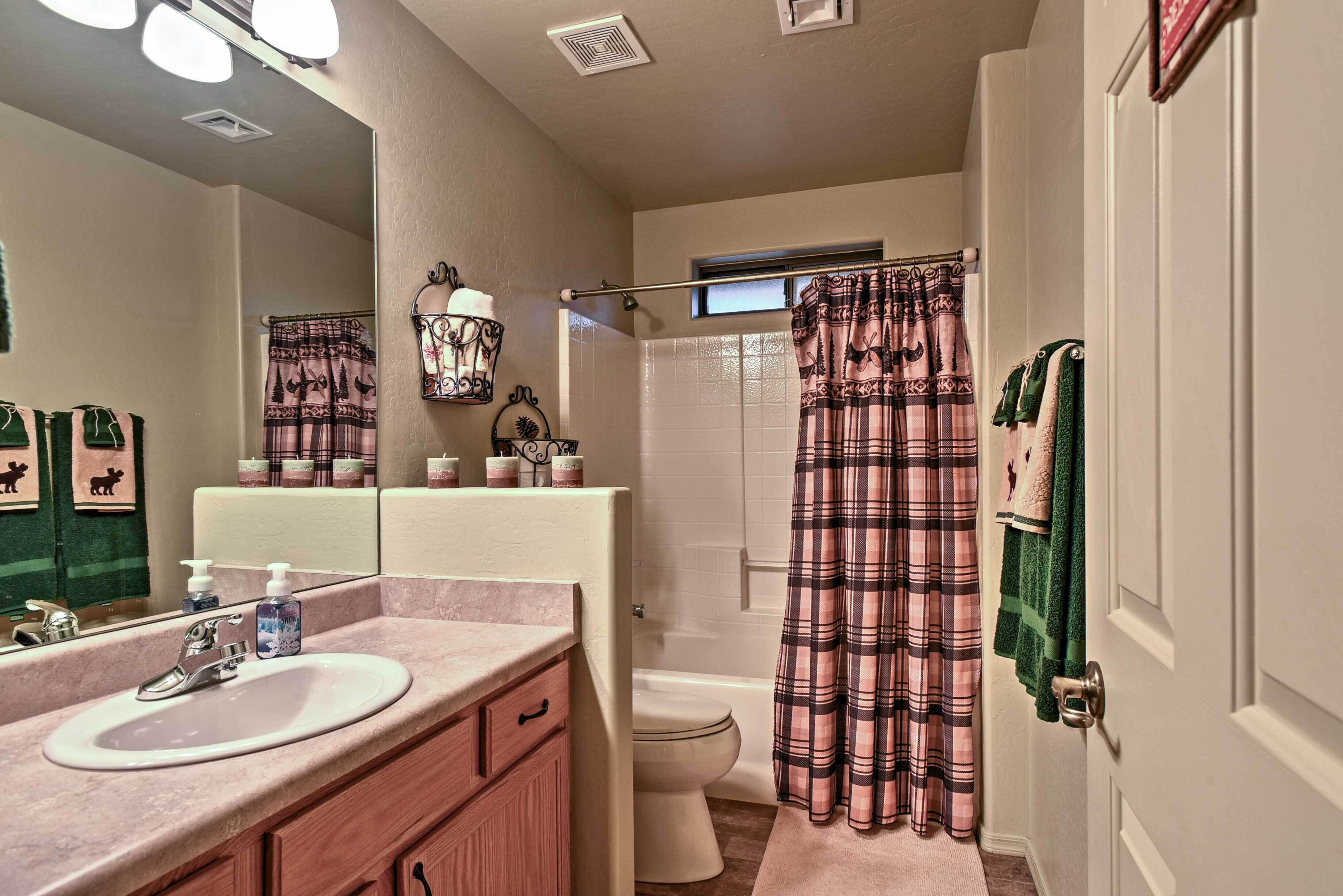 A bathroom with a sink, mirror, toilet, and shower curtain.