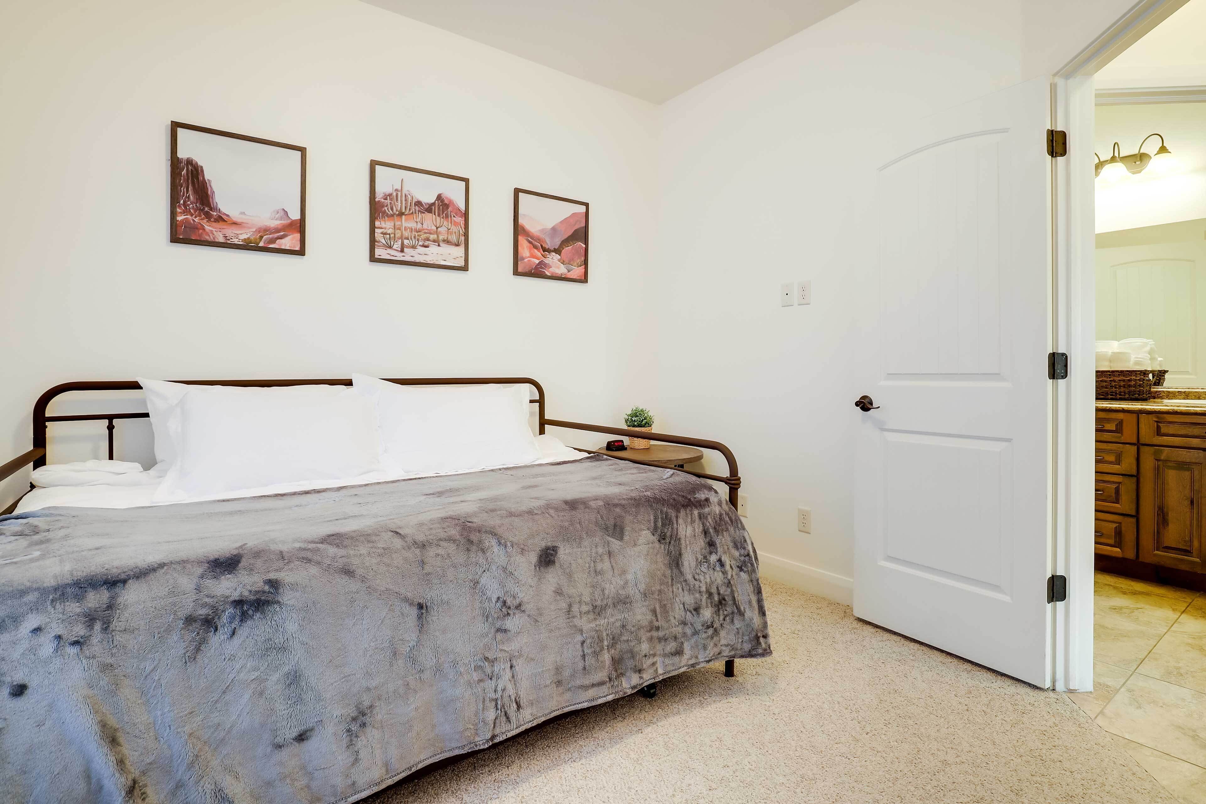 A bedroom with a bed, a small bedside table, and three framed pictures on the wall.