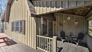 Une terrasse en bois avec une table de pique-nique et deux chaises, une véranda et un bâtiment en bois aux bardages verticaux.