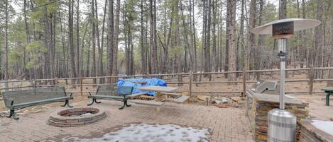 A picnic area with benches, a fire pit, a grill, and a heater.