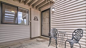 A building entrance with two metal chairs and a small table, a door with a sign, and a window with blinds. - Luxe Fraser Condo: Community Pool and Hot Tub Open (Fraser)