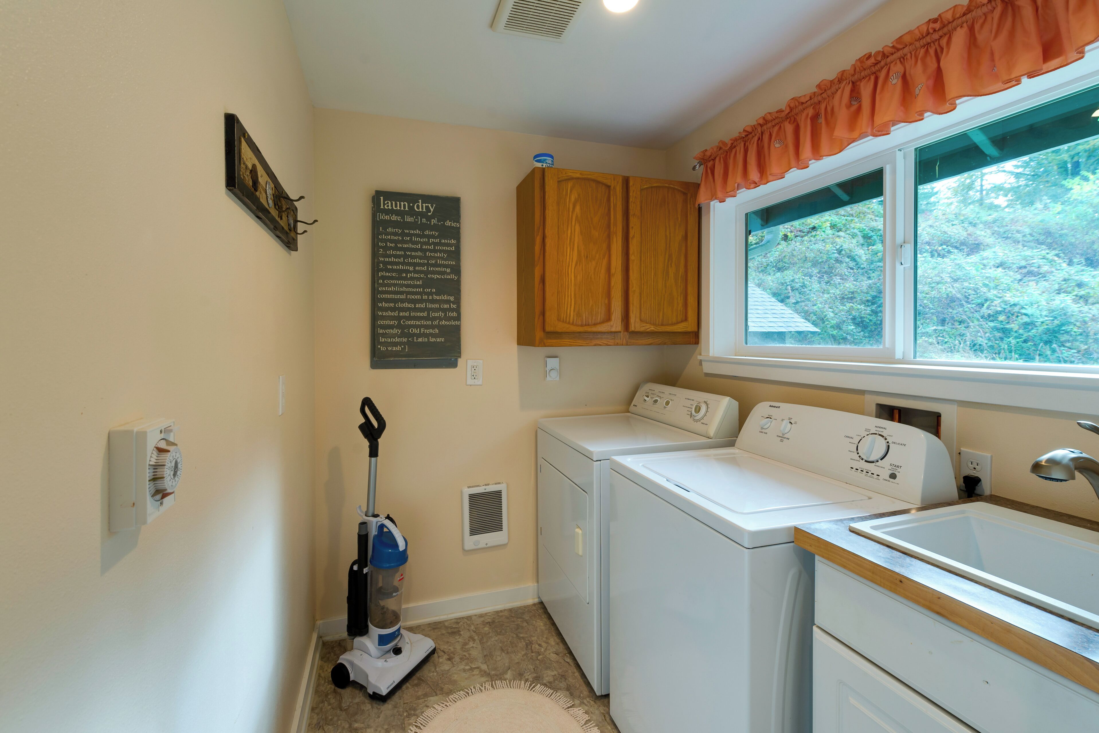 A laundry room with a washing machine, dryer, and a vacuum cleaner.