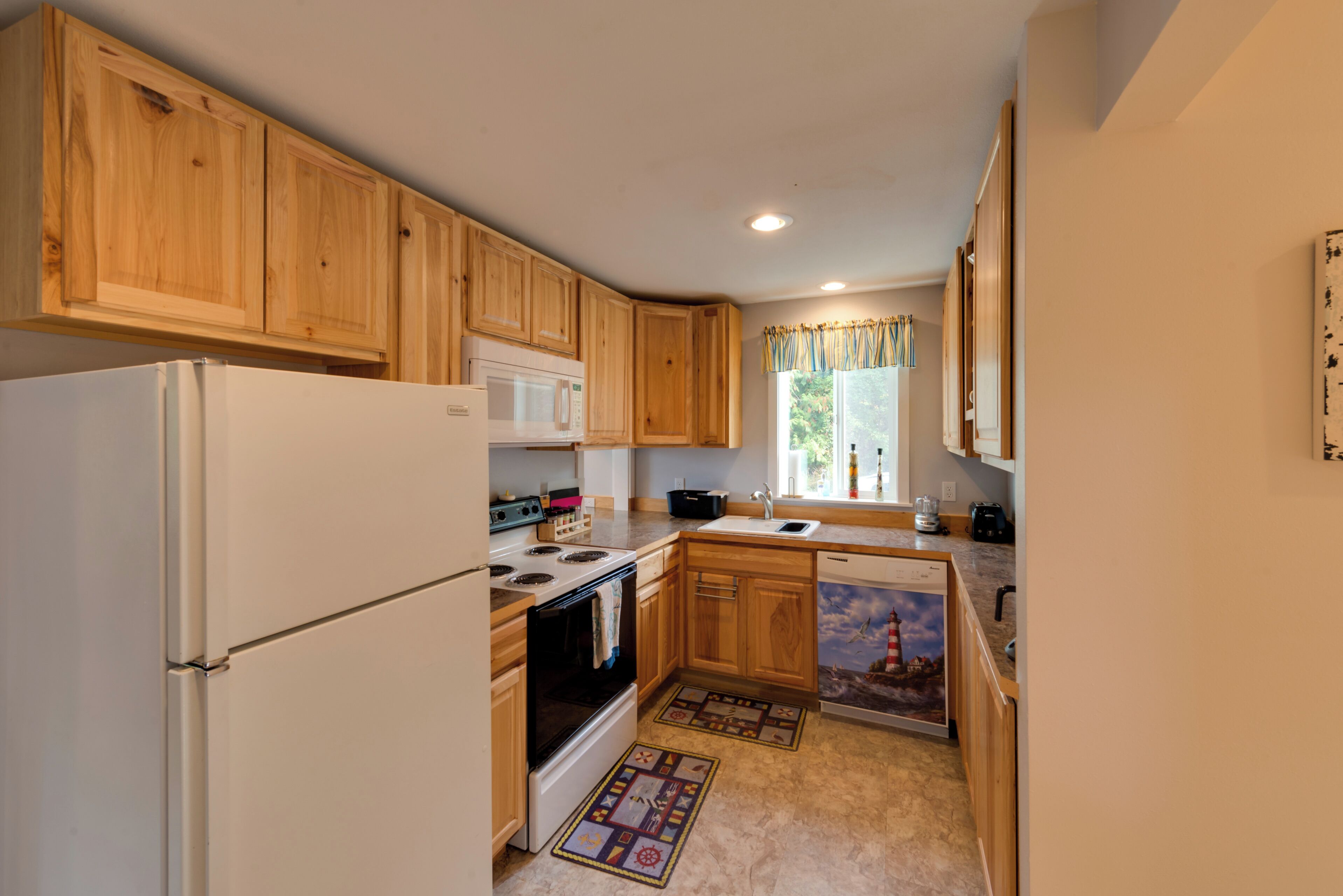 A kitchen with wooden cabinets, a white refrigerator, a microwave, an oven, and a dishwasher.